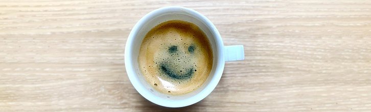Eine Tasse mit Kaffee; in der Crema ist ein Smiley zu sehen